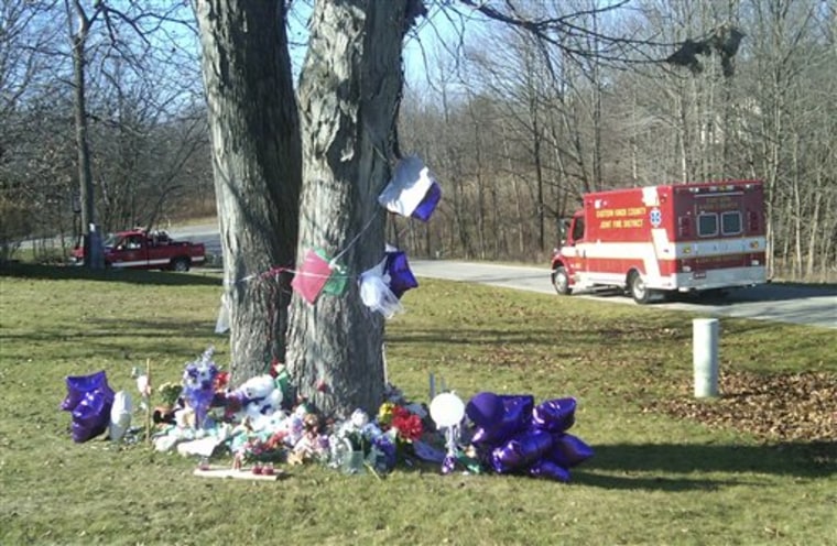 Memorial items surround a tree Tuesday in the front yard of the home in Howard, Ohio, where three people were stabbed. The 13-year-old daughter of one of the victims was rescued, but the bodies of the other three were found days later.
